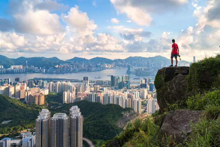 photographer standing on the top of Cliff above Hong kong cityscape