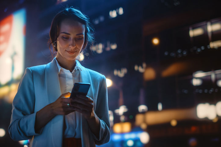 Woman Walking At Night Looking At Phone