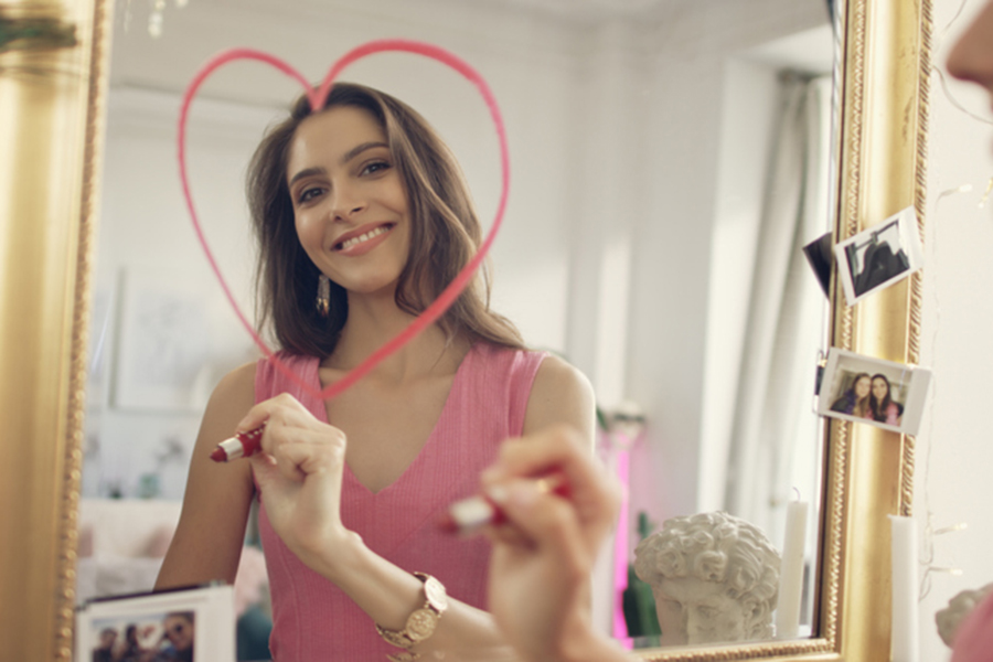 Beautiful brunette drawing red heart on a mirror. Date preparations